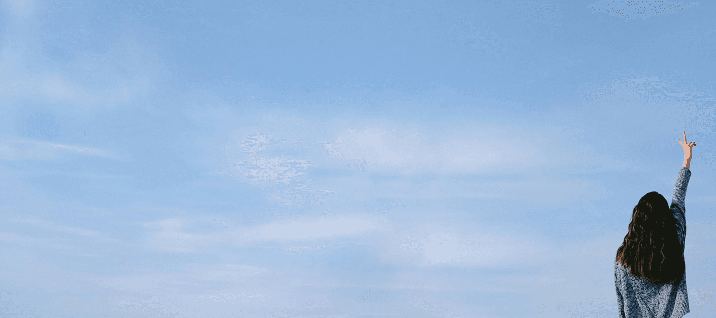 Donna di spalle che fa il segno della vittoria con cielo azzurro di sfondo