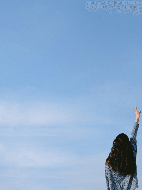 Donna di spalle che fa il segno della vittoria con cielo azzurro di sfondo