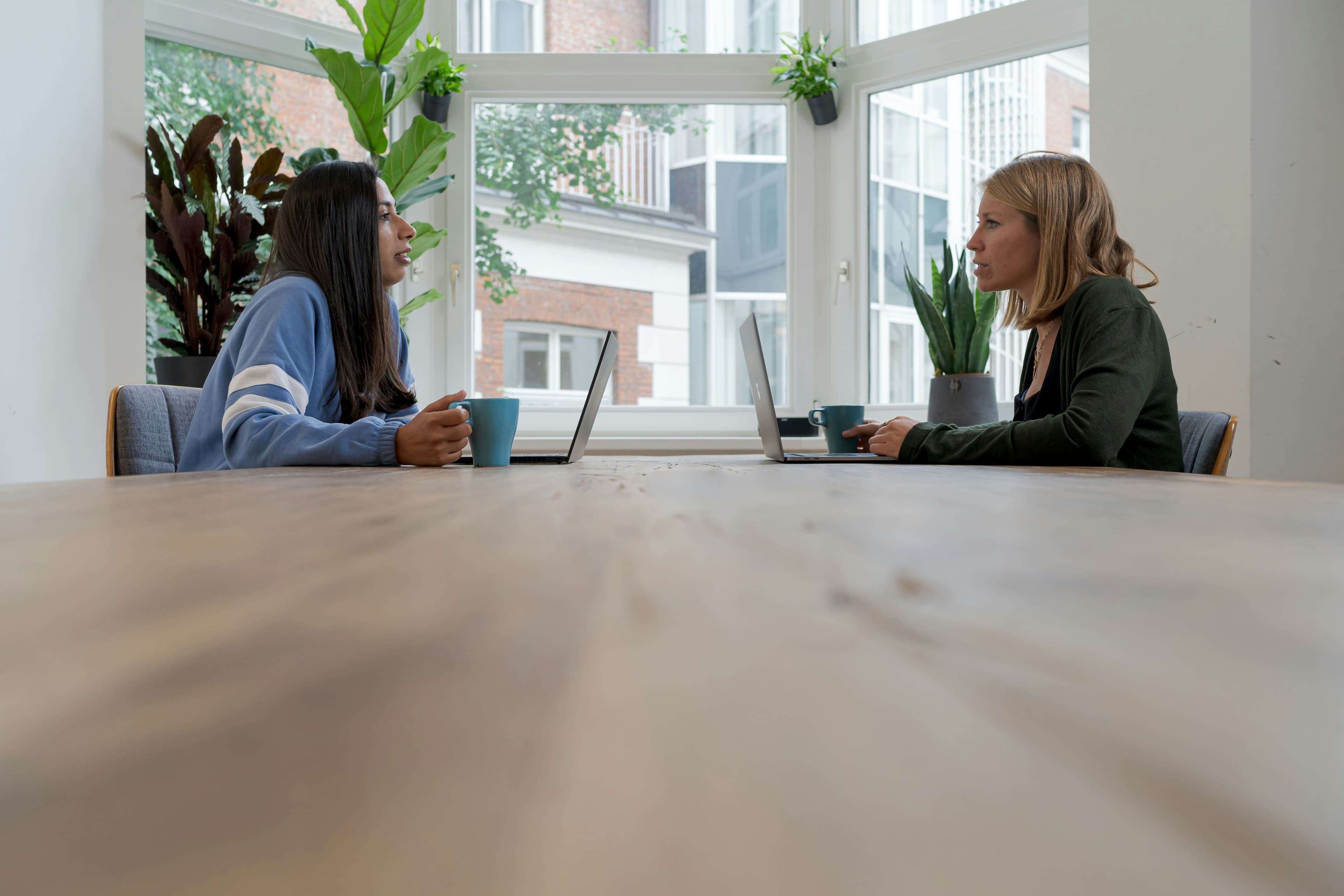 Due professioniste in conversazione strategica in un ambiente di lavoro moderno, esempio di relazione professionale cross-generazionale