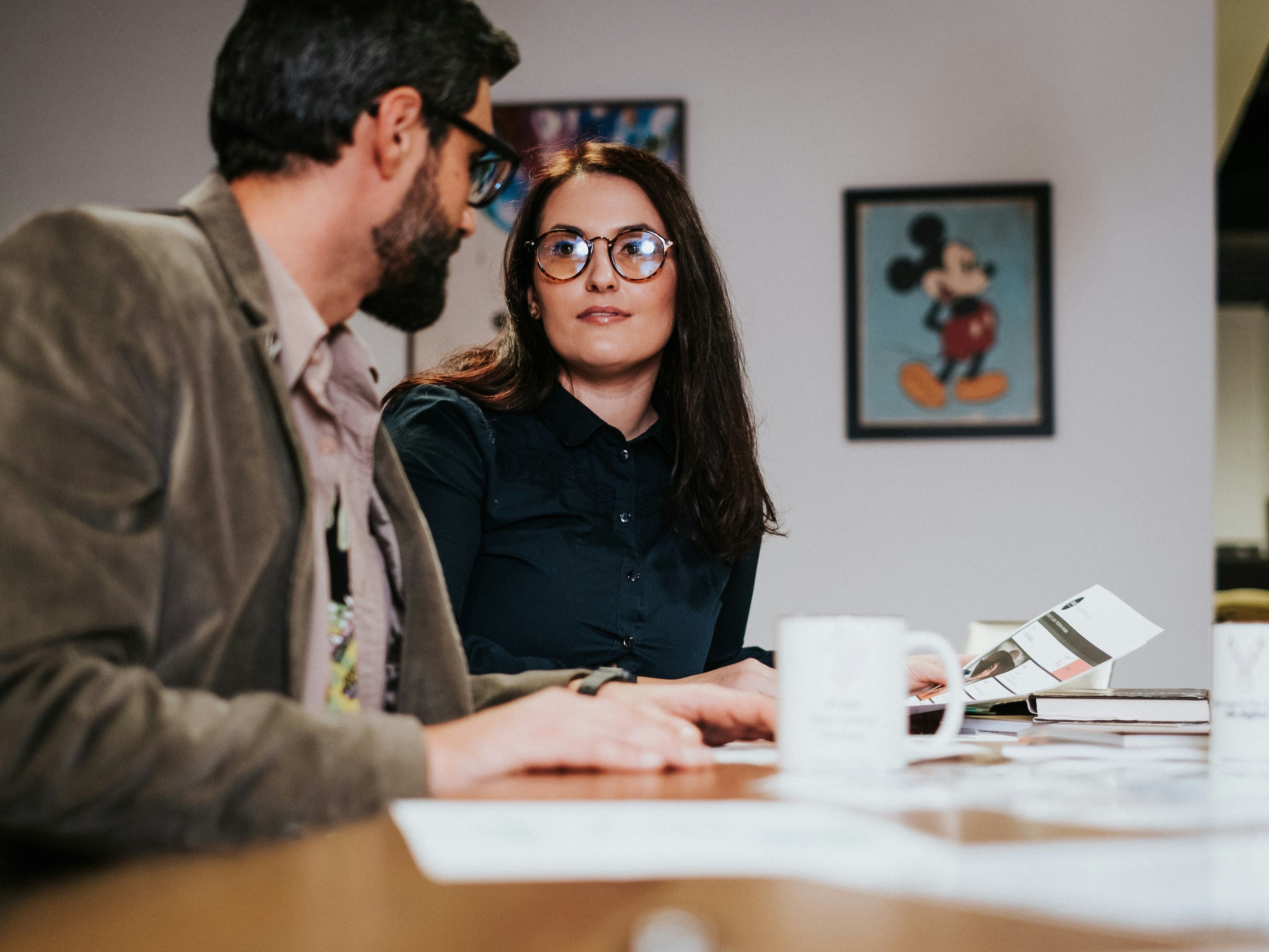 Donna e uomo in conversazione professionale al tavolo, contesto di comunicazione assertiva e gestione strategica del dialogo